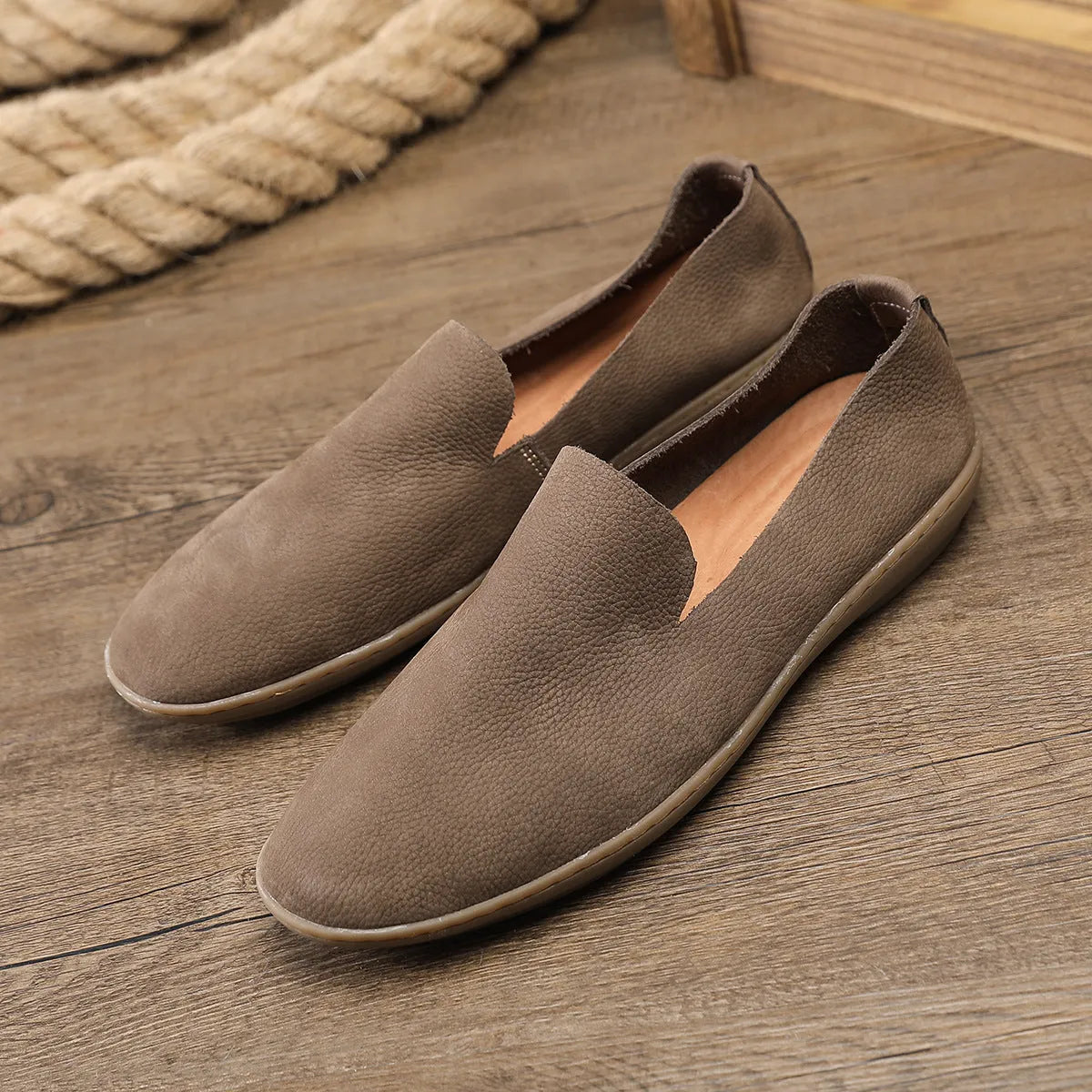 Handmade grey men's low-top leather shoes with a flat wedge rubber sole on a plain background.