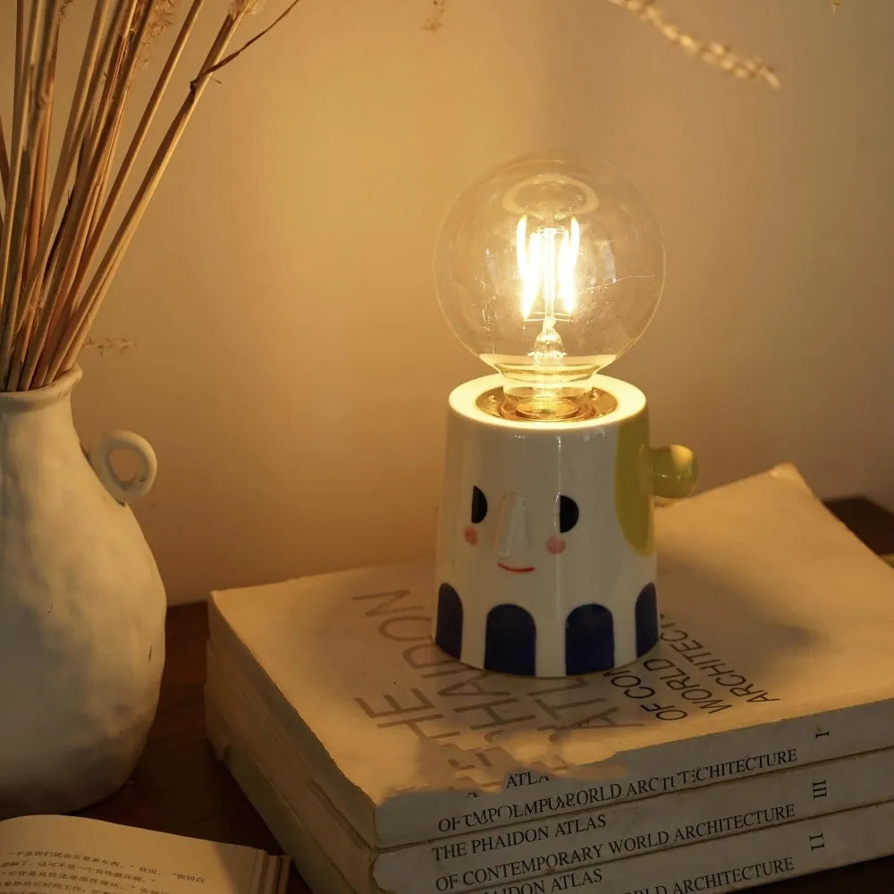 Handmade ceramic table lamp with a spherical ball headlight design on a bedside table.