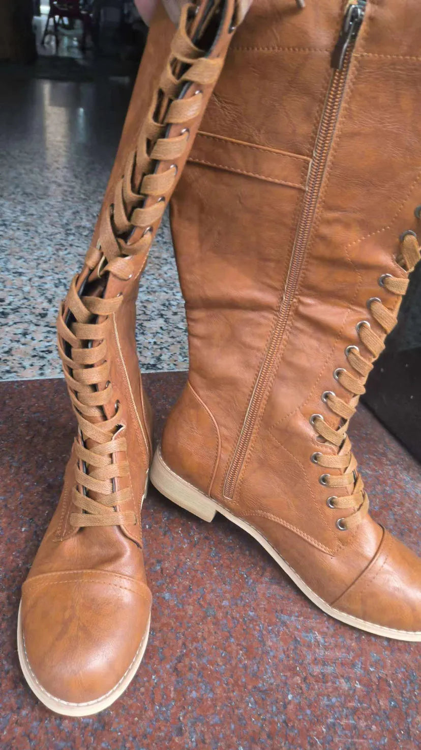 Women's black knight ankle boots with a cross-strap design across the front.