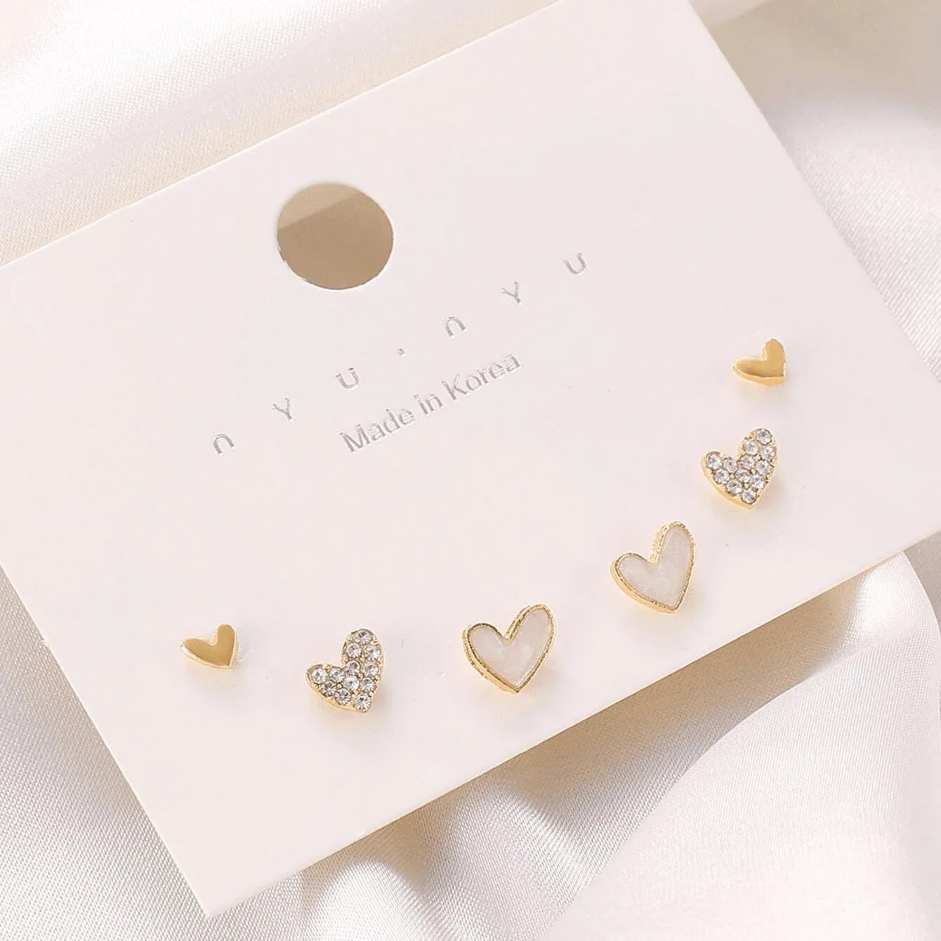 Three pairs of heart-shaped earrings with electroplated alloy construction in gold, black, pink and black-white colours