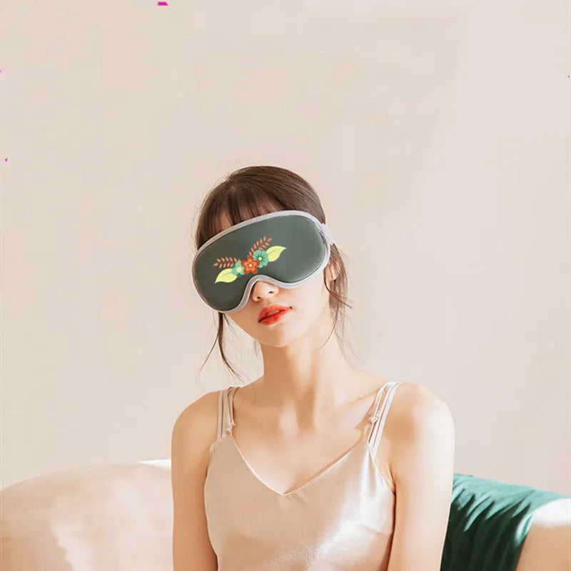 Green portable eye SPA massage goggles with USB cable on a grey background.