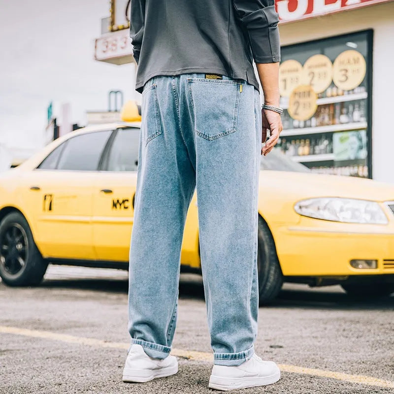 Man wearing dark blue loose straight-cut cotton jeans with a mid-waist and zipper fly.
