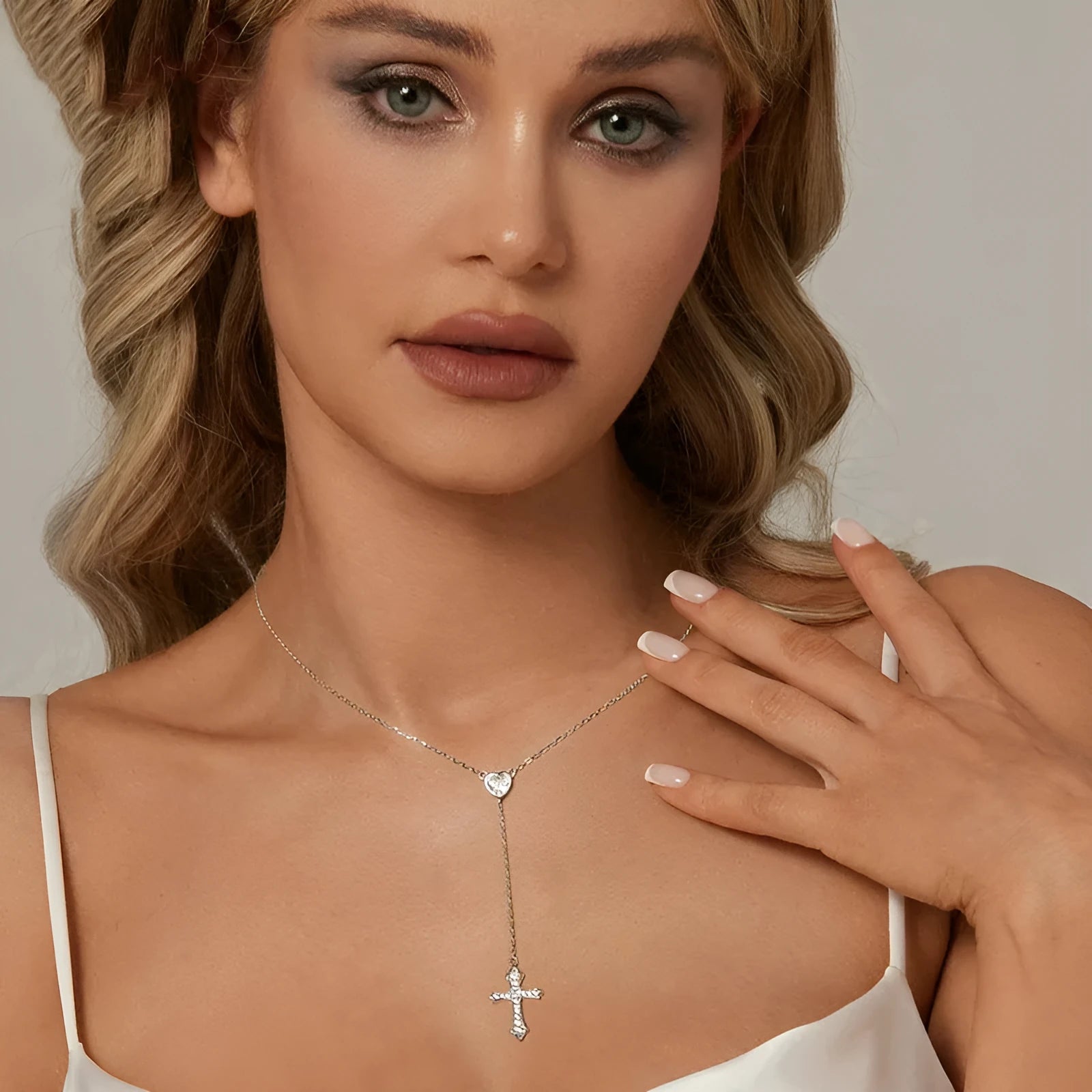 Close-up of a delicate silver love cross pendant on a thin O-ring chain, designed for V-neck wear.