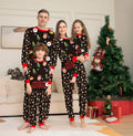 Family wearing matching red plaid Christmas pajamas with dog in matching pet pajamas