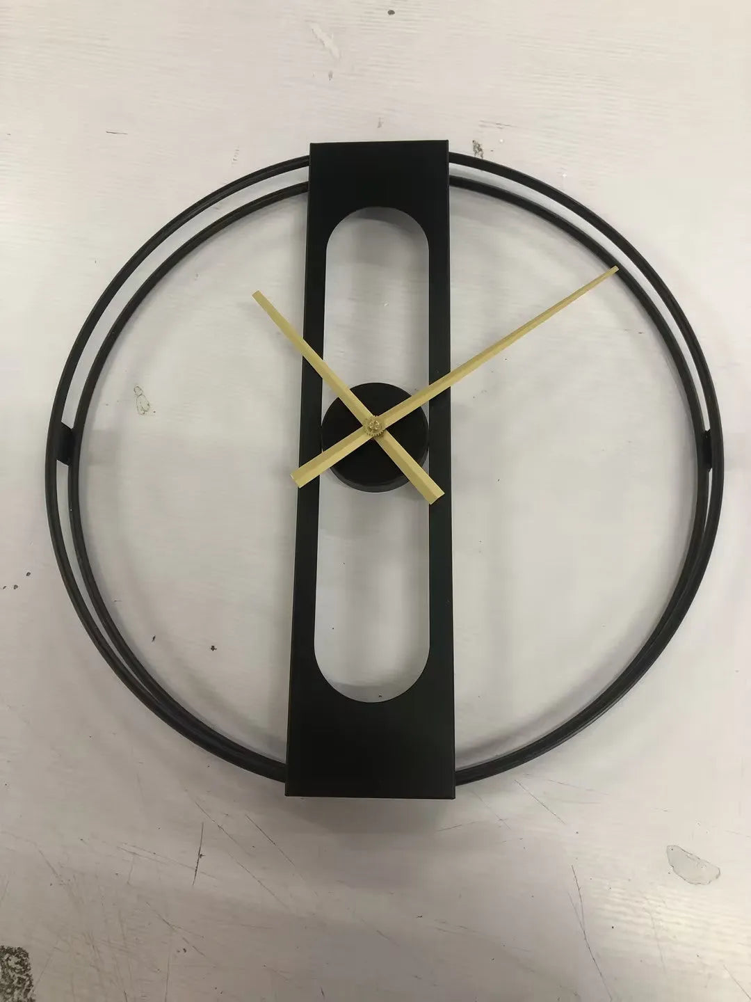 Round metal wall clock with 50cm diameter in black or gold colour on a wall.