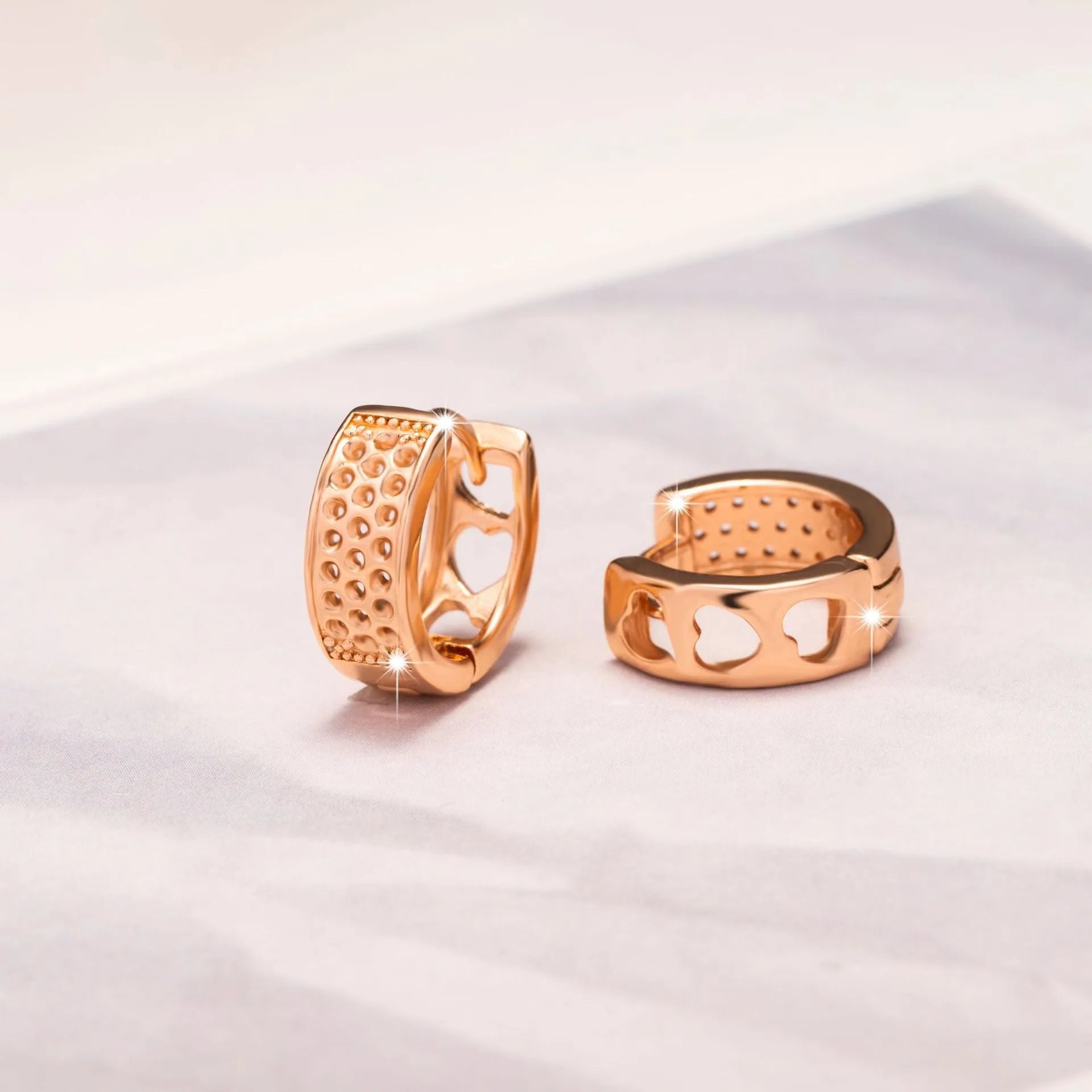 Circular rose gold earrings with three cut-out heart shapes