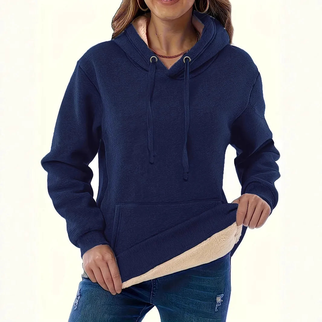 A woman wearing a loose thick black hooded sweater with side pockets and a 3D textured pattern.