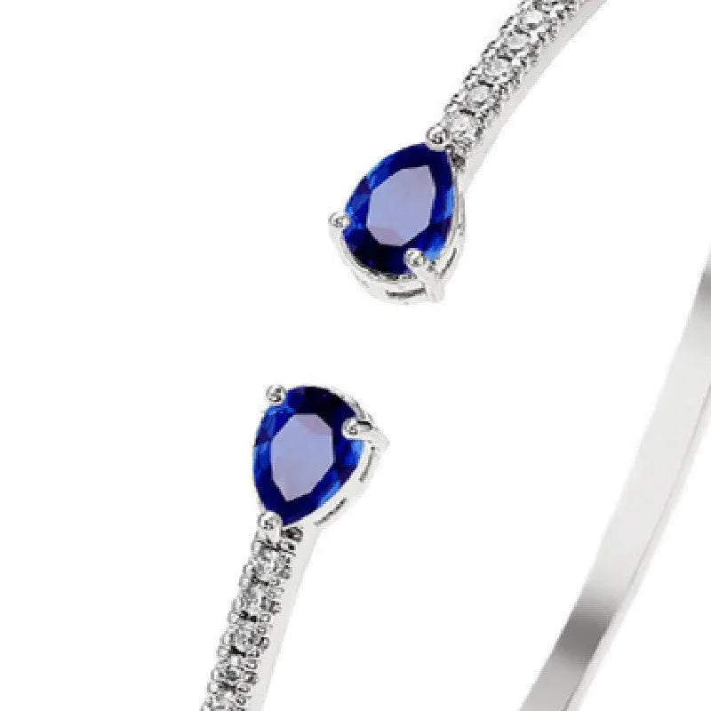 Close-up of a solid copper bracelet with inlaid white zircon stones on a blue background.