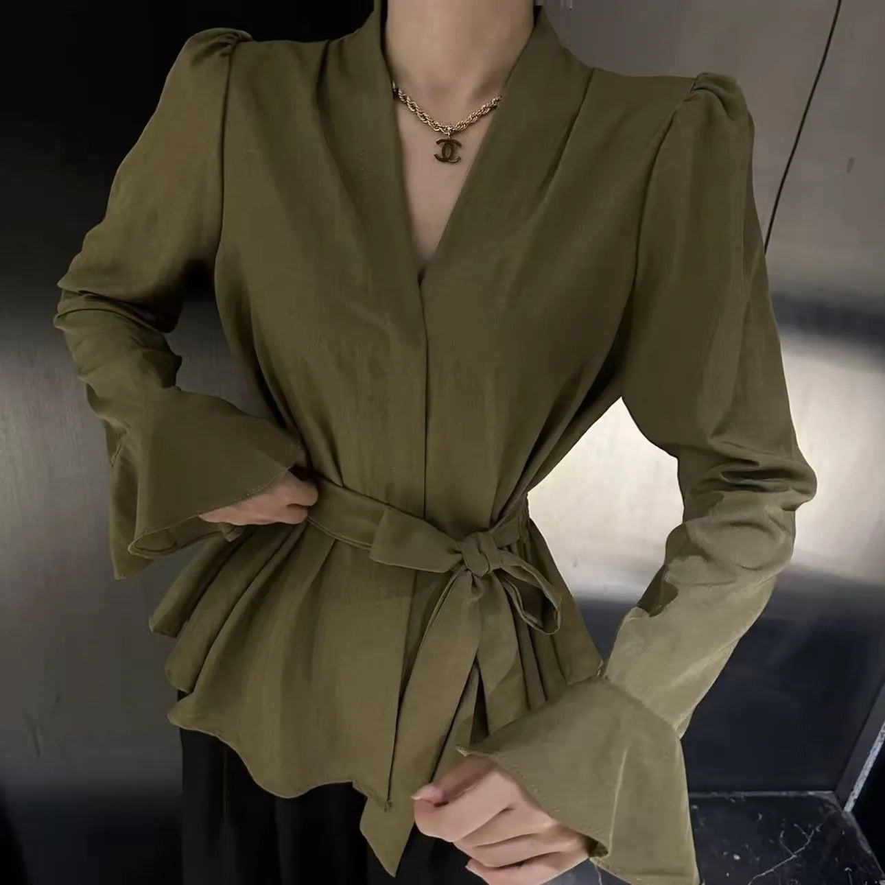 Women's black long sleeve shirt with irregular French collar, front tie, and bell sleeves