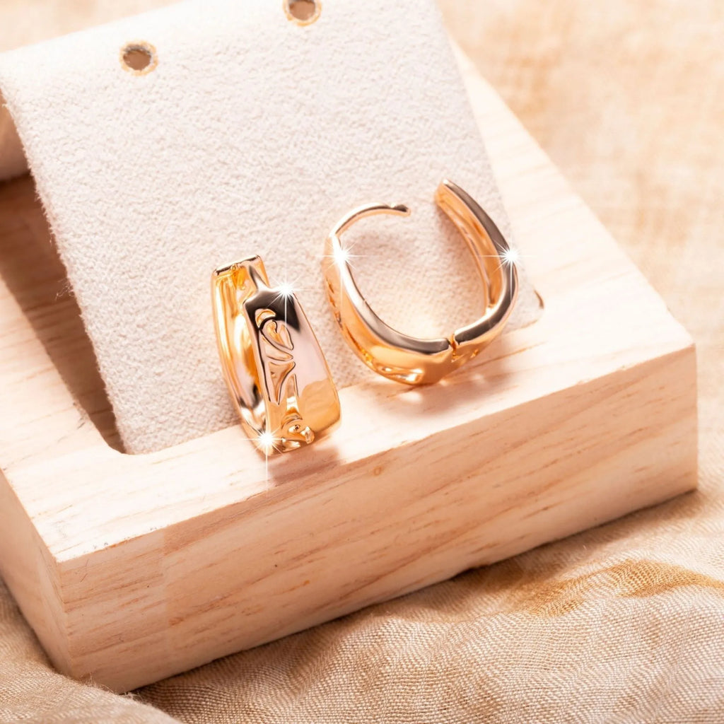 Rose gold hollow carved U-shaped copper earrings on light background