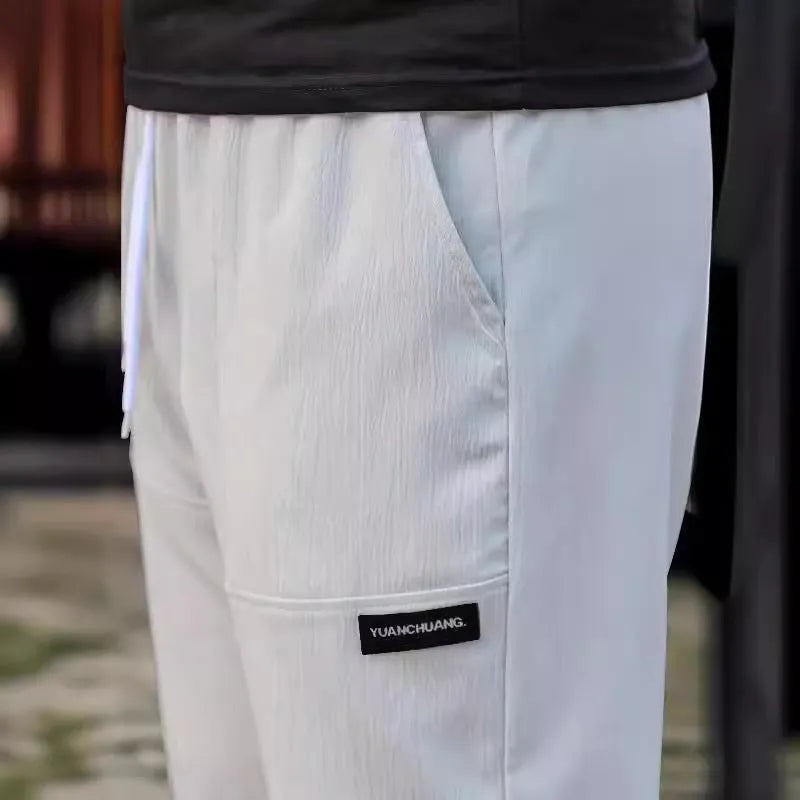 Men's polyester trousers for spring and autumn in light grey, shown flat.