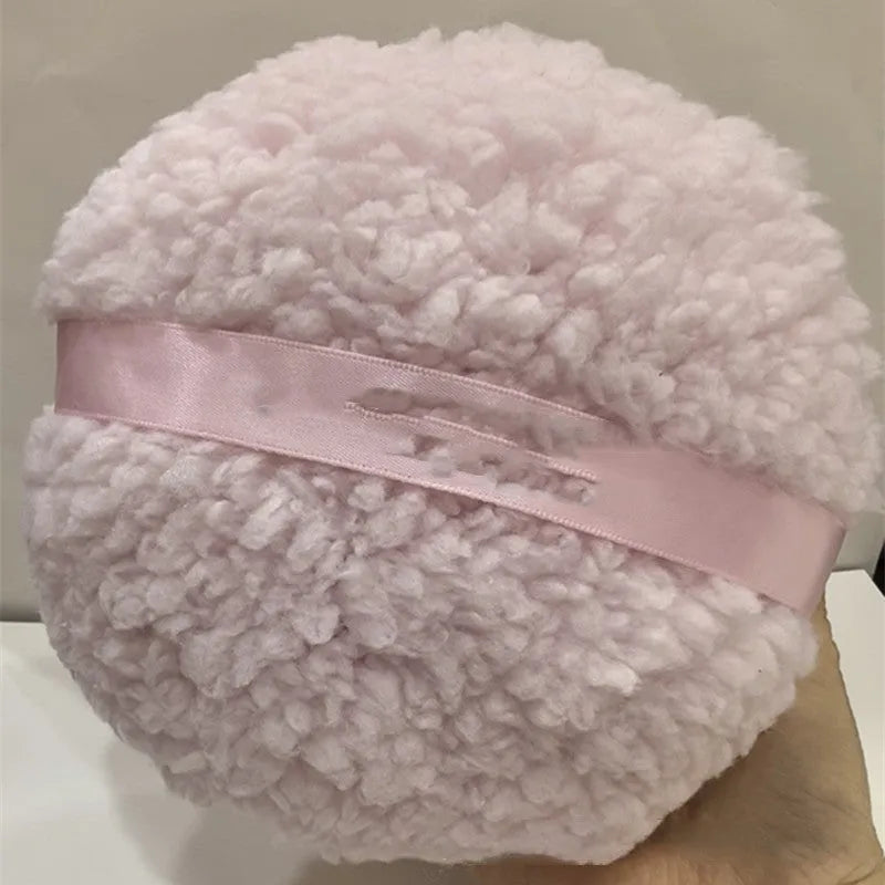 Oversized soft plush makeup powder puff in pink, white, and skin colour on a white background