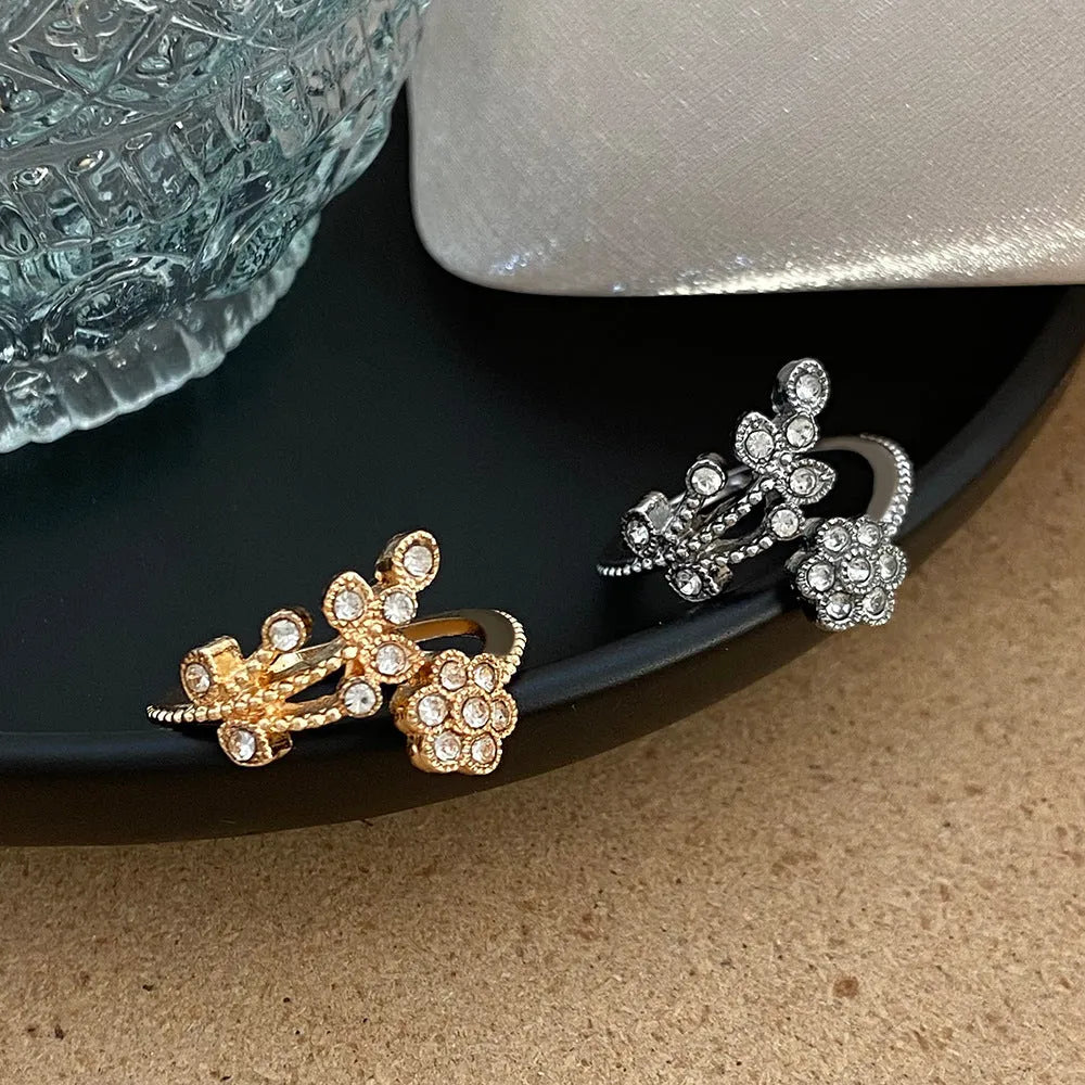 Women's open ring with diamond flower and leaf pattern in copper, shown in gold and white colour options.