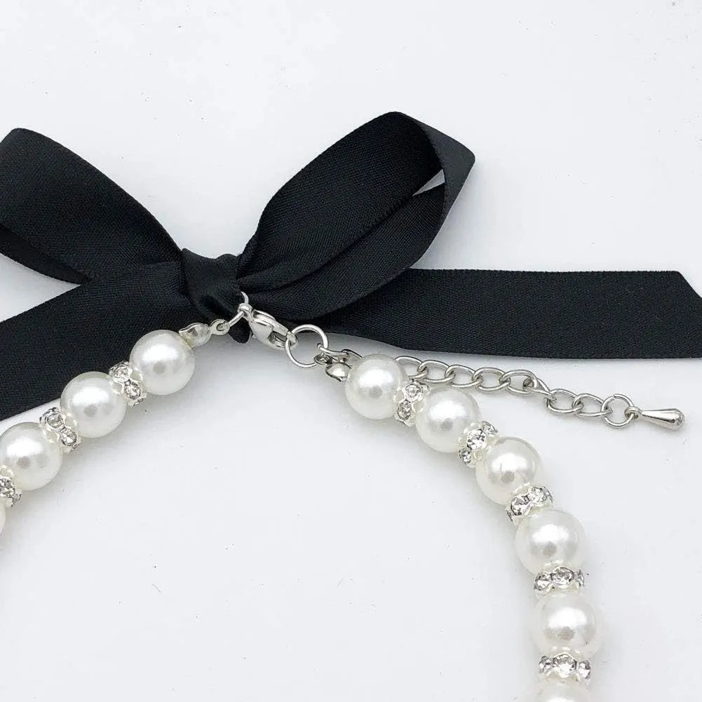 Small dog wearing adjustable pearl and rhinestone necklace with soft ribbon bow in blue colour