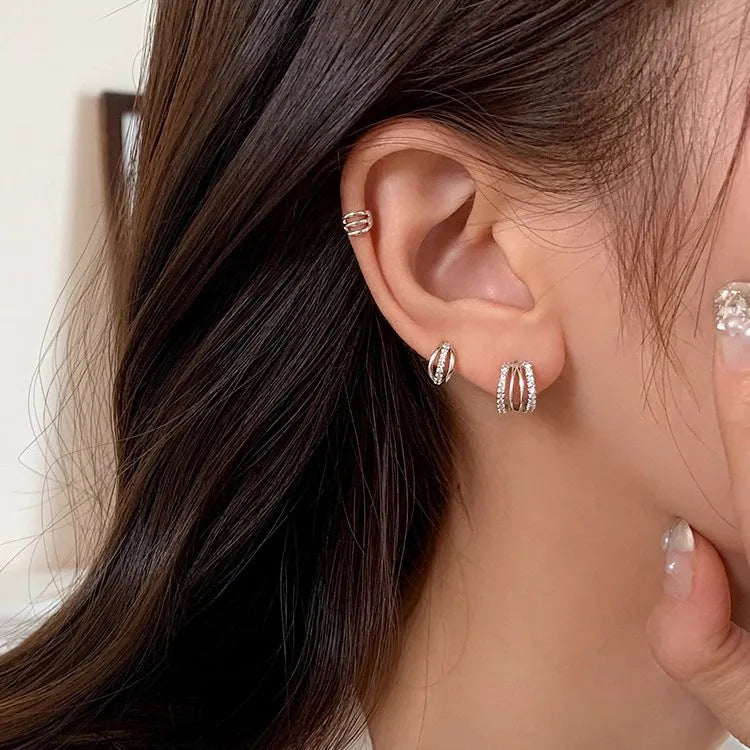 Minimalist geometric 925 sterling silver earrings with silver posts on a plain background.