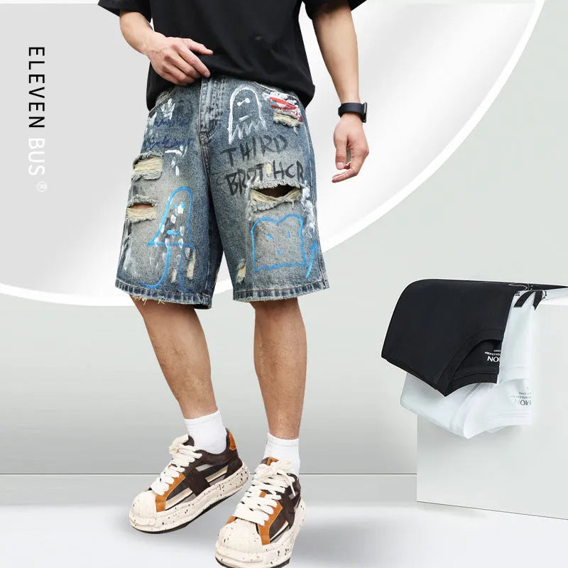 Blue men's ripped denim shorts with graffiti-style detailing and straight-leg cut.