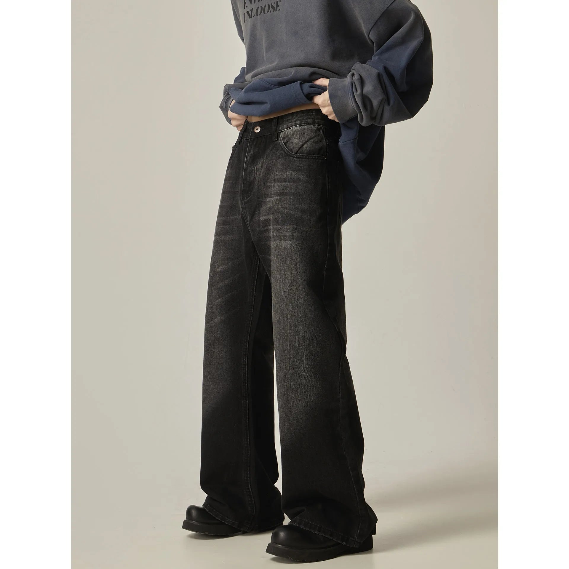 Black loose straight-leg retro jeans on a hanger, showing the front view with zipper fly.