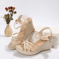 Women's beige cloth wedge sandals with a fish mouth toe design on a plain background.