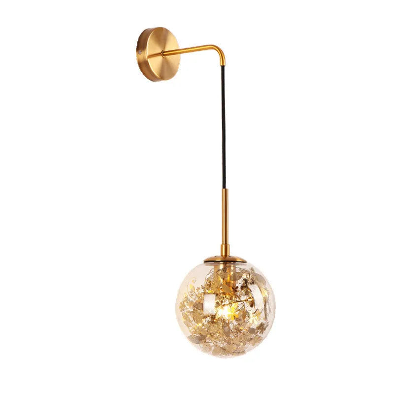 Modern minimalist glass wall lamp with golden flower finish, shown mounted beside a bed.