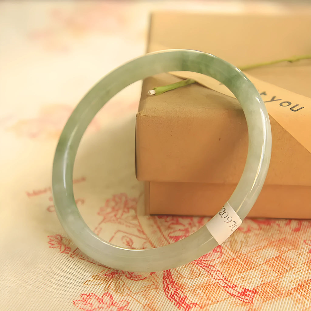 Green jade waxy geometric bracelet with Chinese-style design on a wrist.