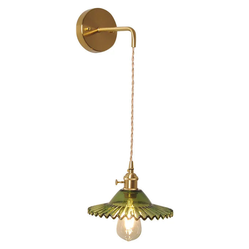 Retro brass copper lotus wall lamp with a glass shade in one of six colours, shown beside a bed.