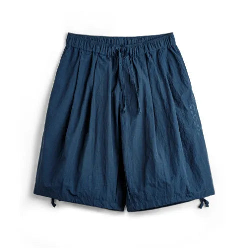 Prussian blue men's loose fit nylon shorts with embroidery on a plain background.