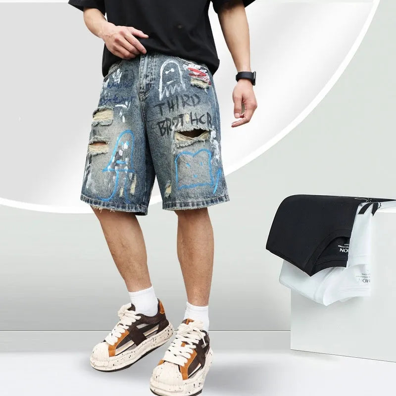 Blue men's ripped denim shorts with graffiti-style detailing and straight-leg cut.
