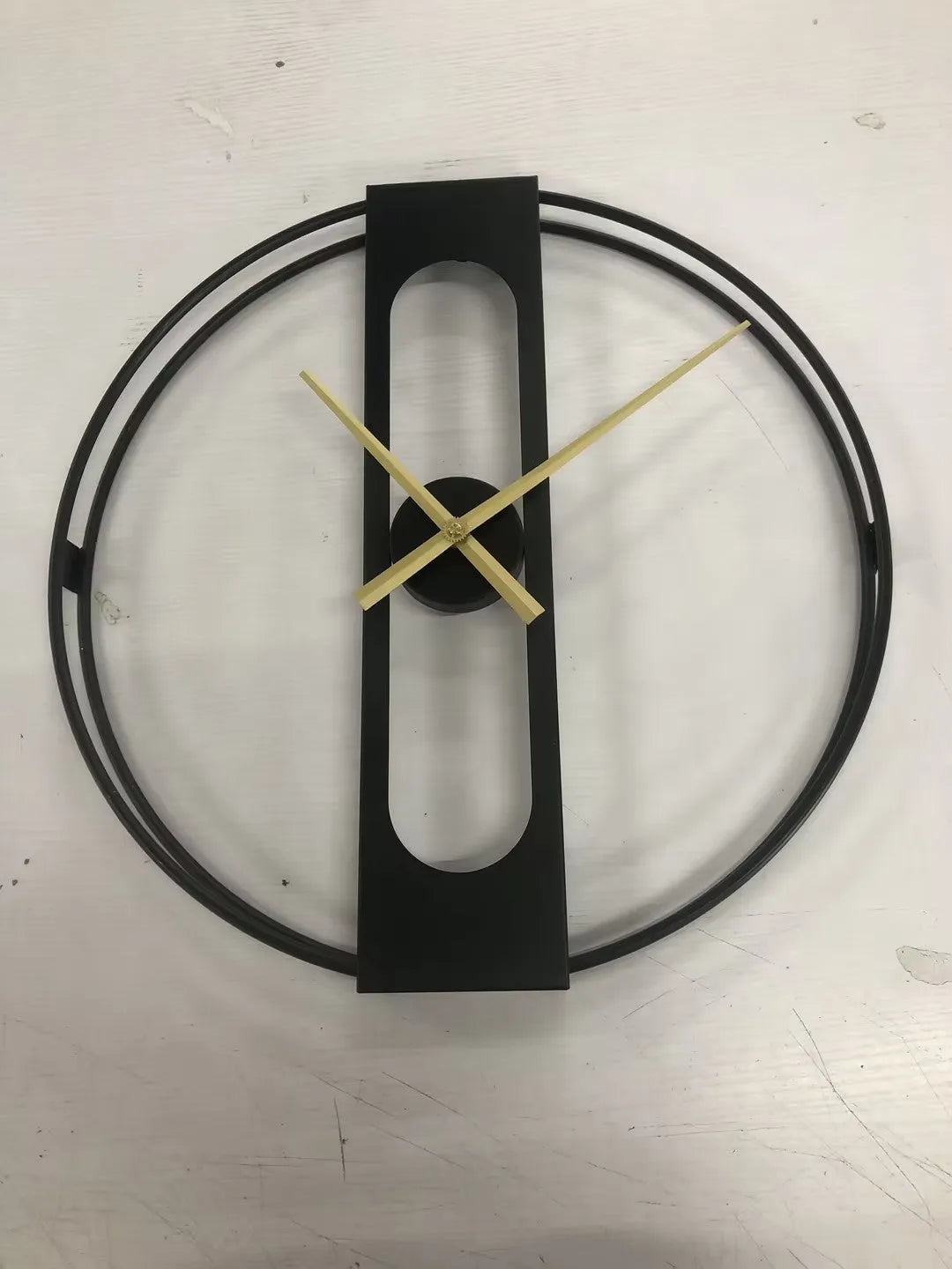 Round metal wall clock with 50cm diameter in black or gold colour on a wall.