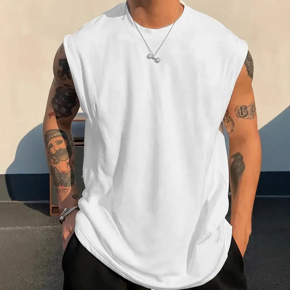 Man wearing a loose, solid-colour cotton sleeveless tank top in a casual setting.
