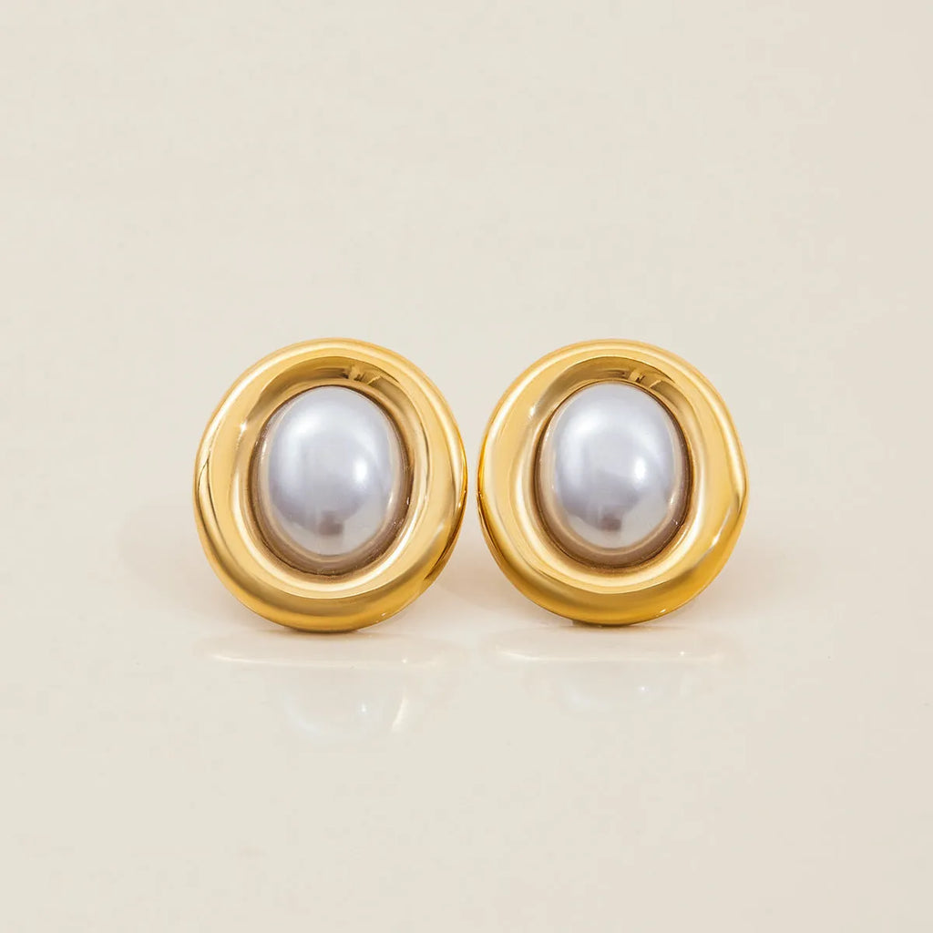 A pair of silver-colour stainless steel stud earrings with a small white pearl detail on a grey background.