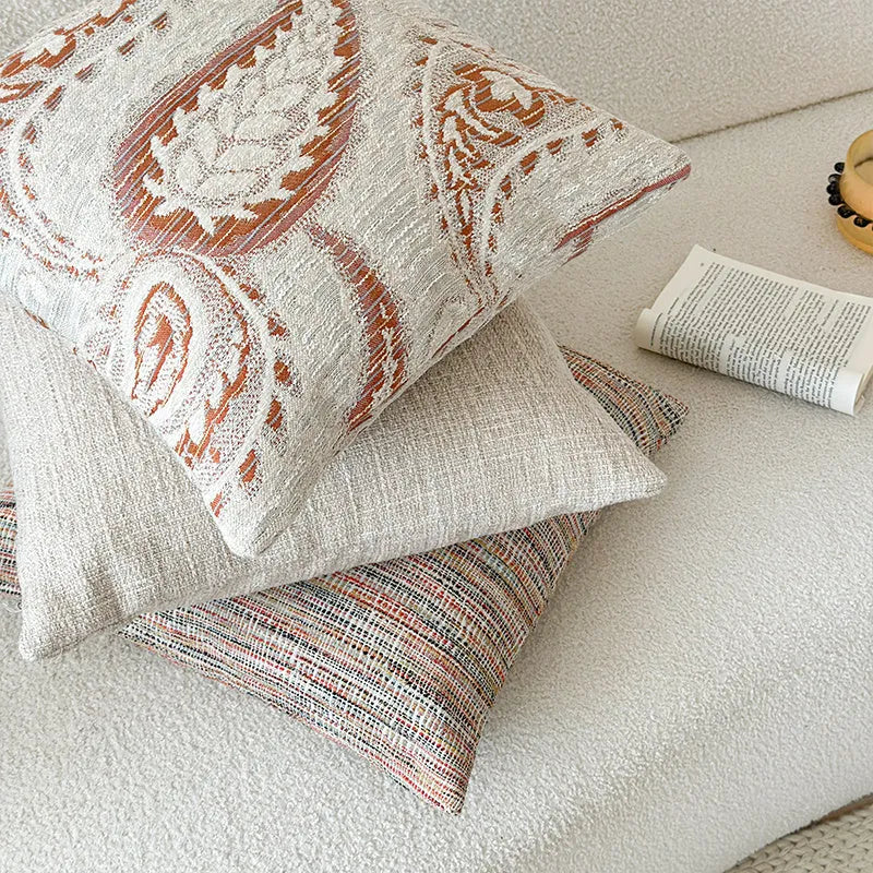 American-style jacquard cushion cover with paisley and flower pattern in amber colours on a sofa.