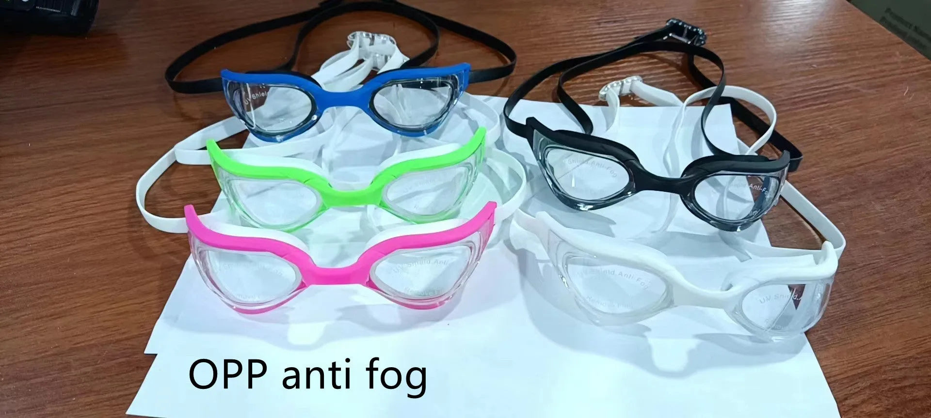 Black and gold plated anti-fog racing swimming goggles with polycarbonate frame on a blue background.