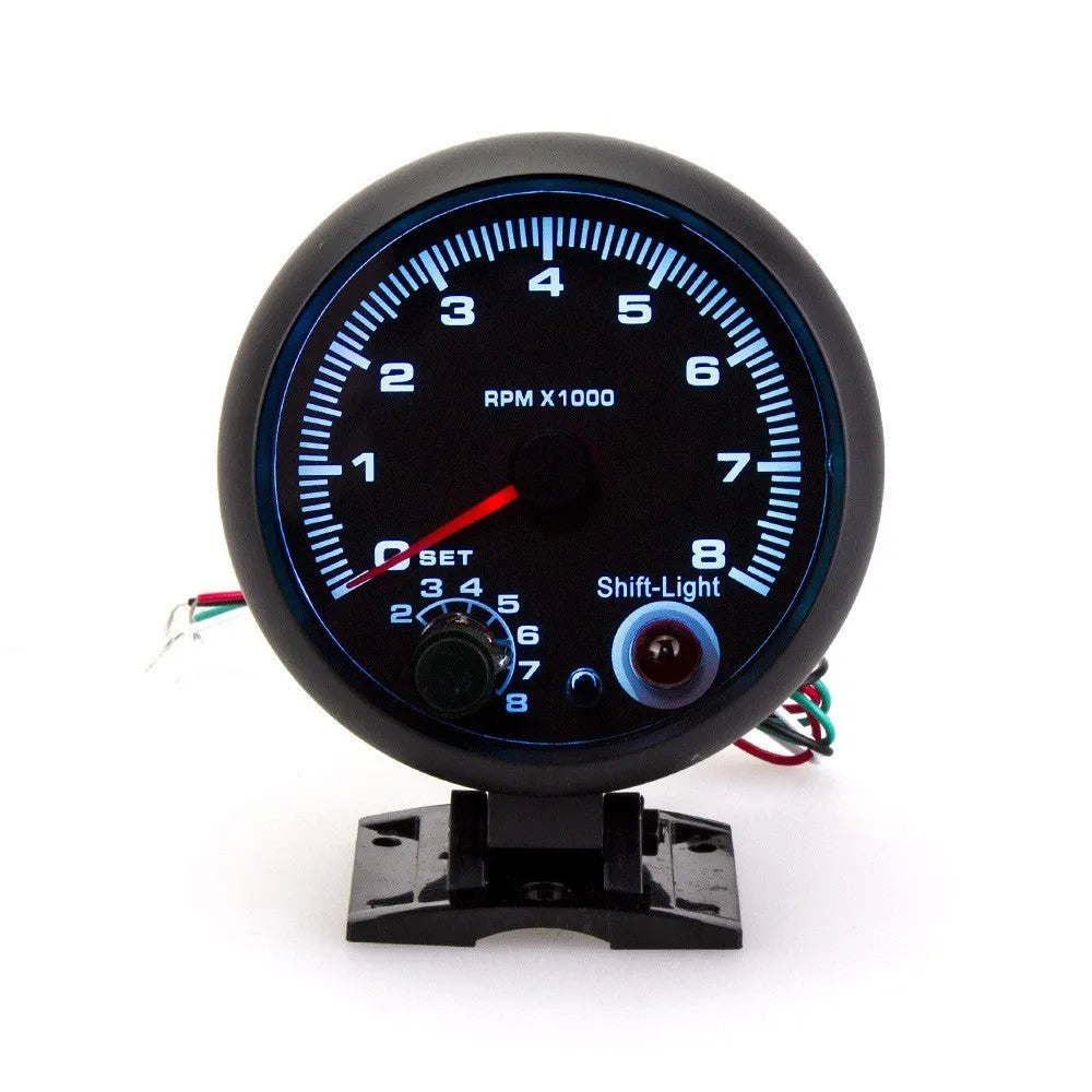 Black plastic universal automotive tachometer with blue light pointer and RPM scale.