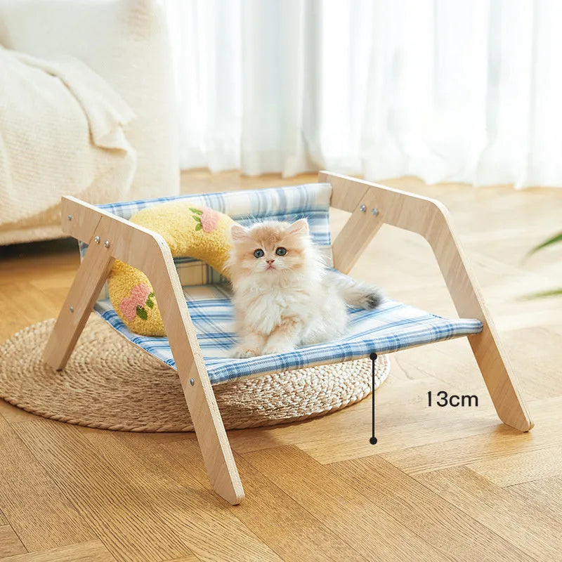 Elevated wooden frame cat bed with soft blue cloth cushion for indoor cats.