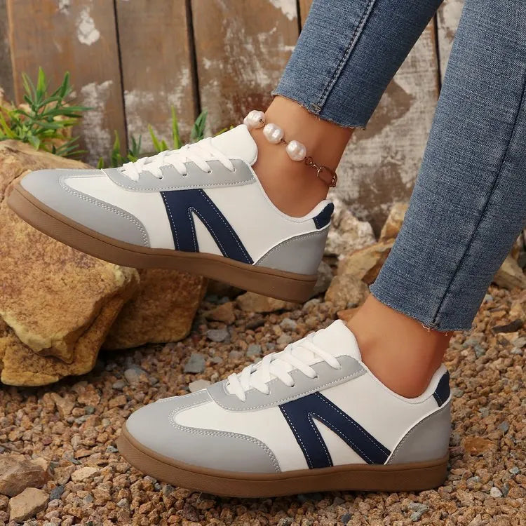 Blue women's low-top hiking shoes with flat rubber sole and lace-up front on artificial grass.