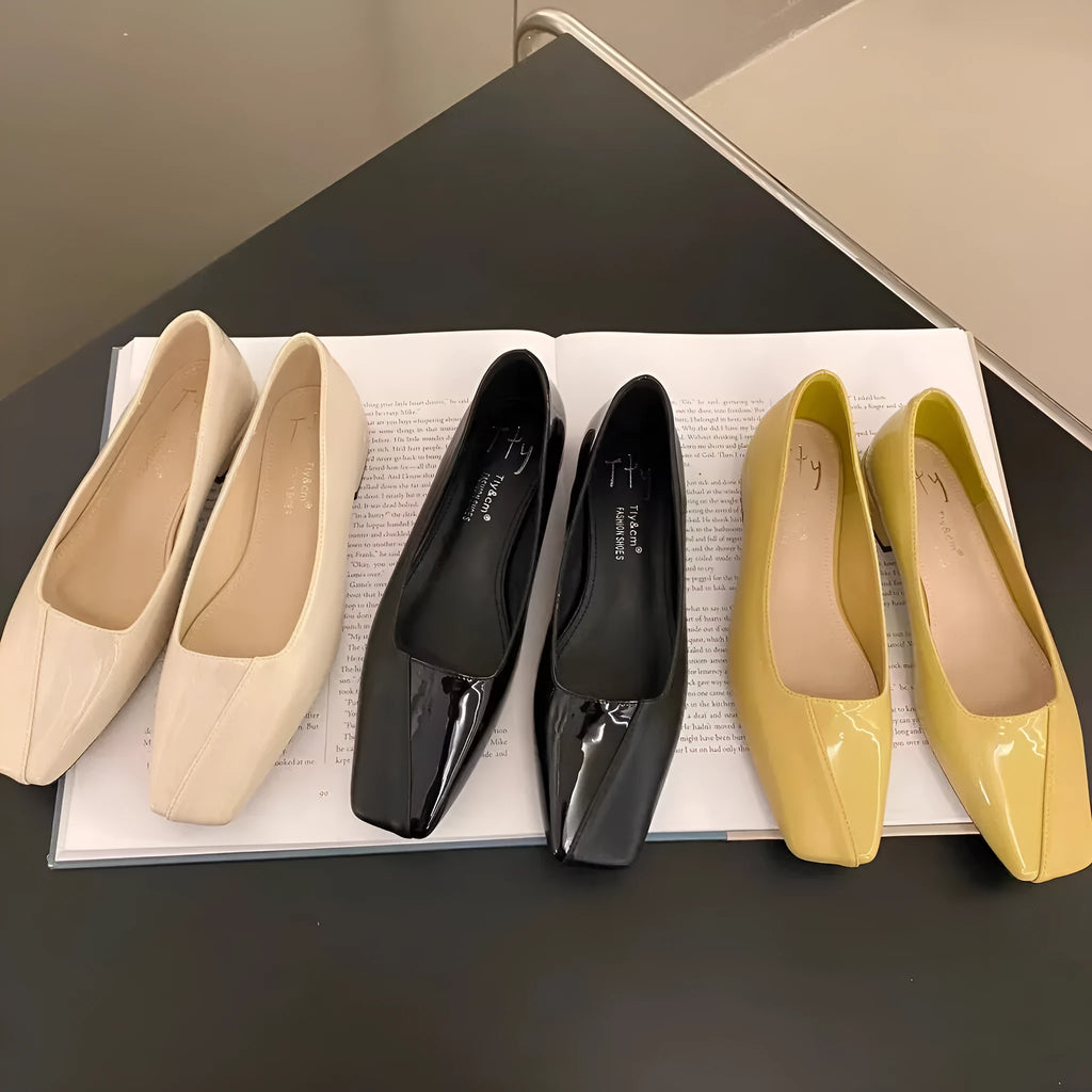 Women's low heel square toe retro pumps in black PU leather with short chunky heel, side view on light background