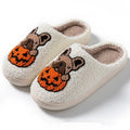 Black and white Halloween pumpkin plush slippers with non-slip rubber soles on a wooden floor