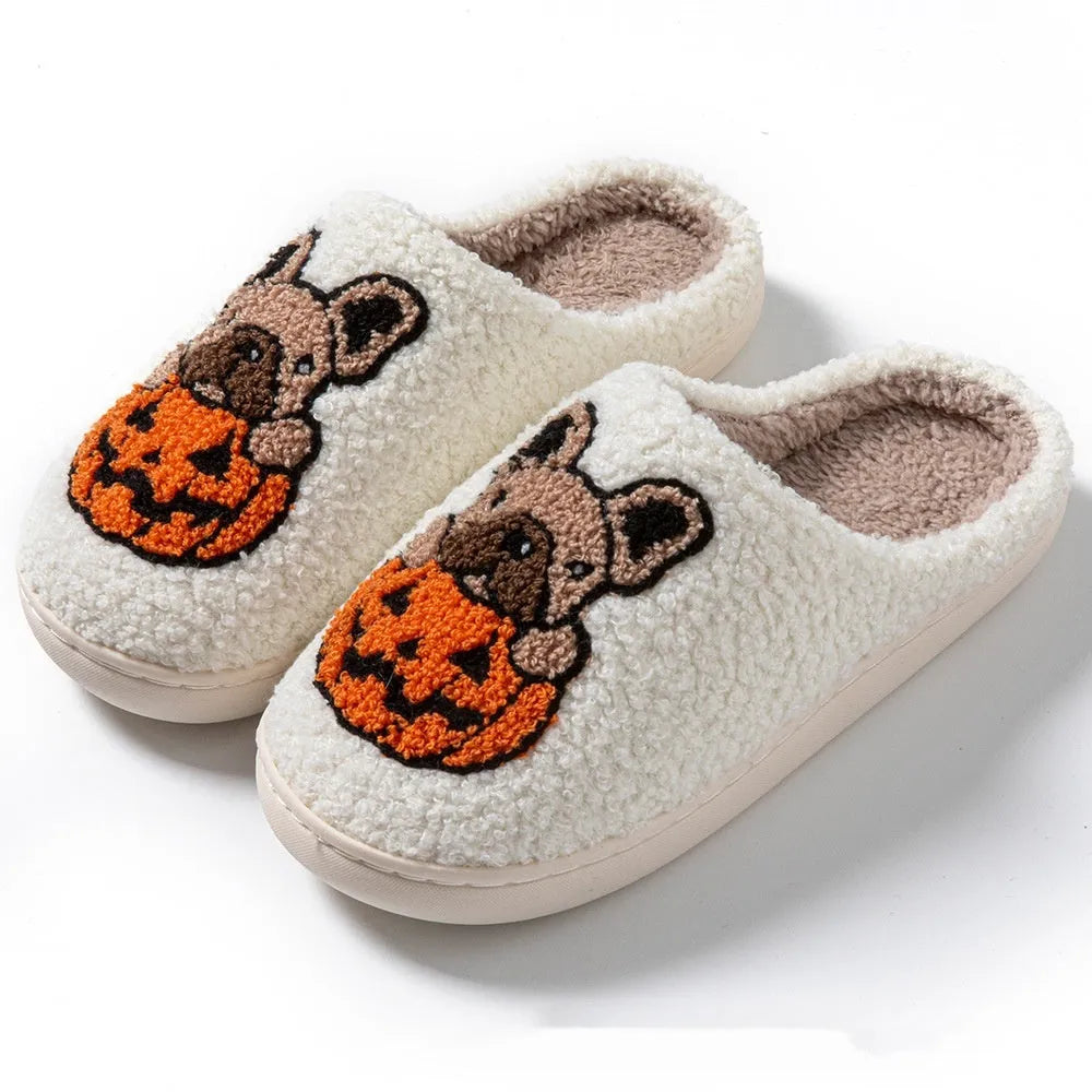 Black and white Halloween pumpkin plush slippers with non-slip rubber soles on a wooden floor