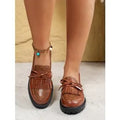 Women's brown and black loafers with bow detail on artificial PU upper, showing slip-on design