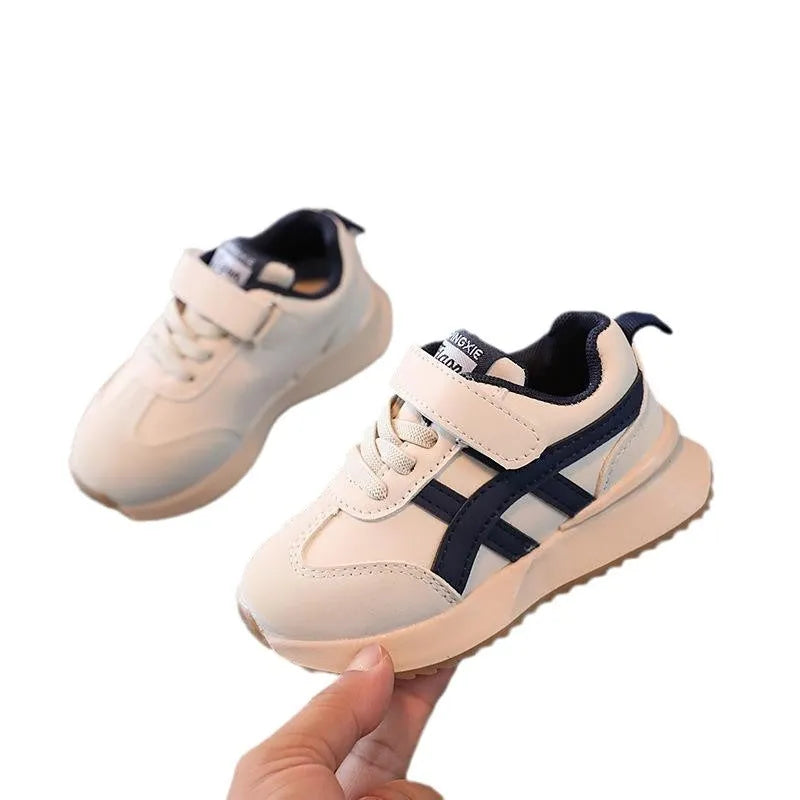 Children's white synthetic leather sneaker with Velcro strap on a neutral background.