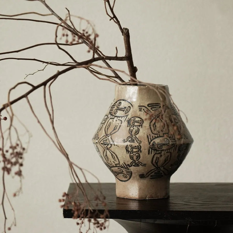 Hand-painted ceramic vase with carved tribal totem art in cylindrical shape.