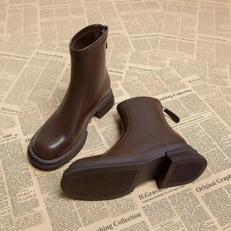 Black women's flat-heel ankle boots with a round toe and back zipper on a white background