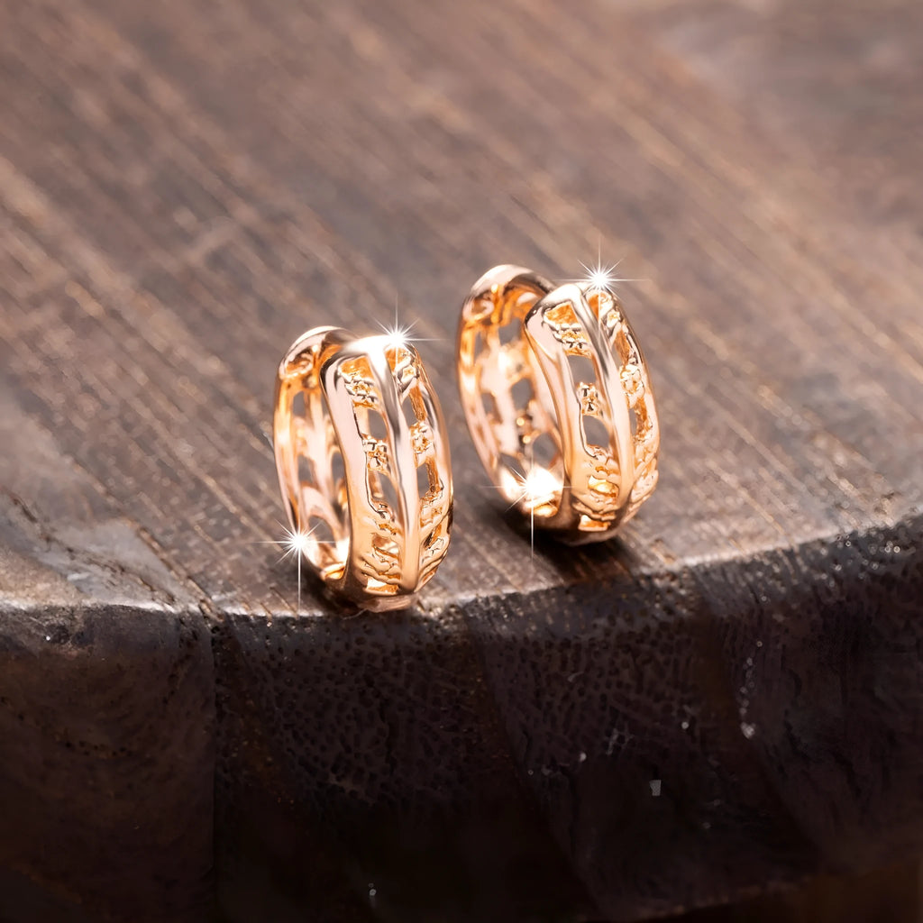 Small rose gold hollowed-out copper earrings with a leaf and a heart pendant design.