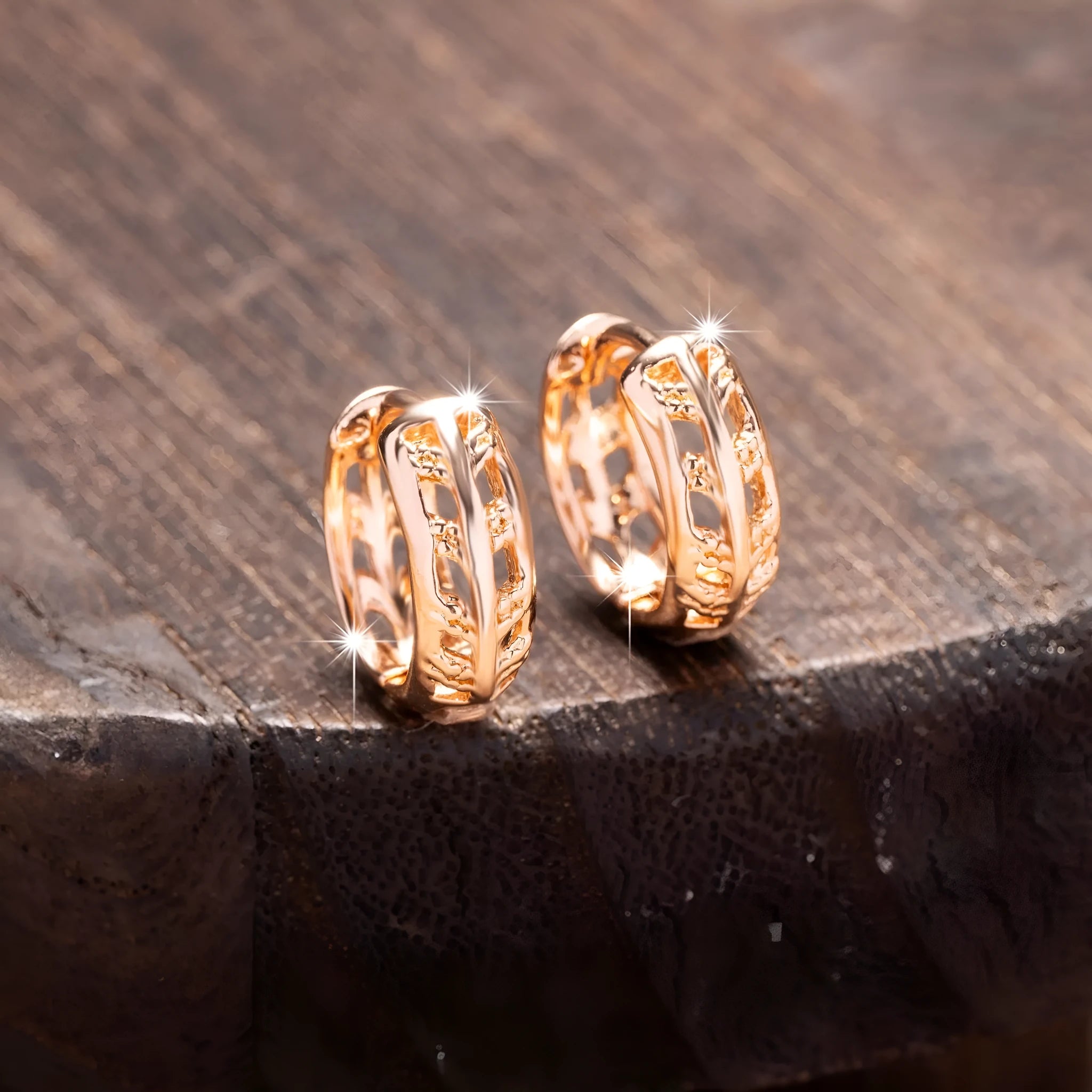 Small rose gold hollowed-out copper earrings with a leaf and a heart pendant design.
