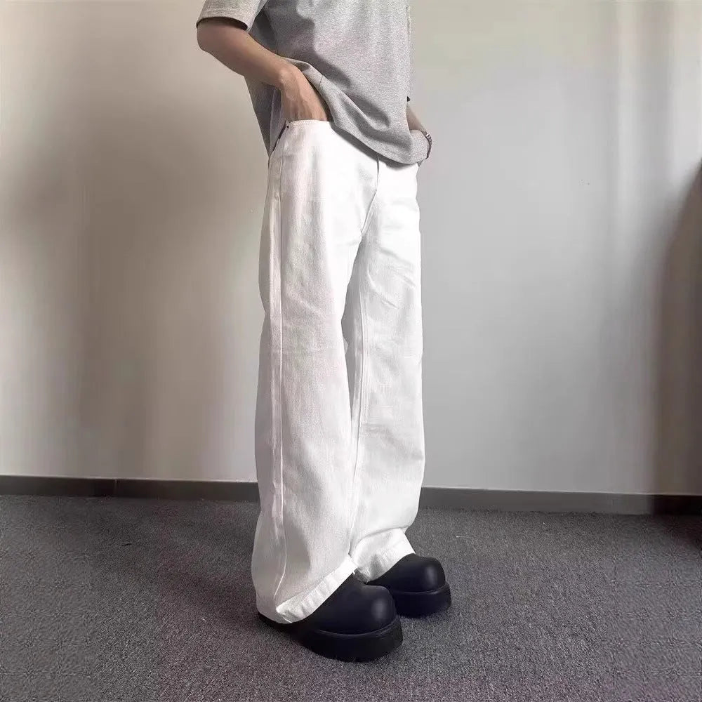 Man wearing loose straight-leg white denim jeans with a wide leg opening.