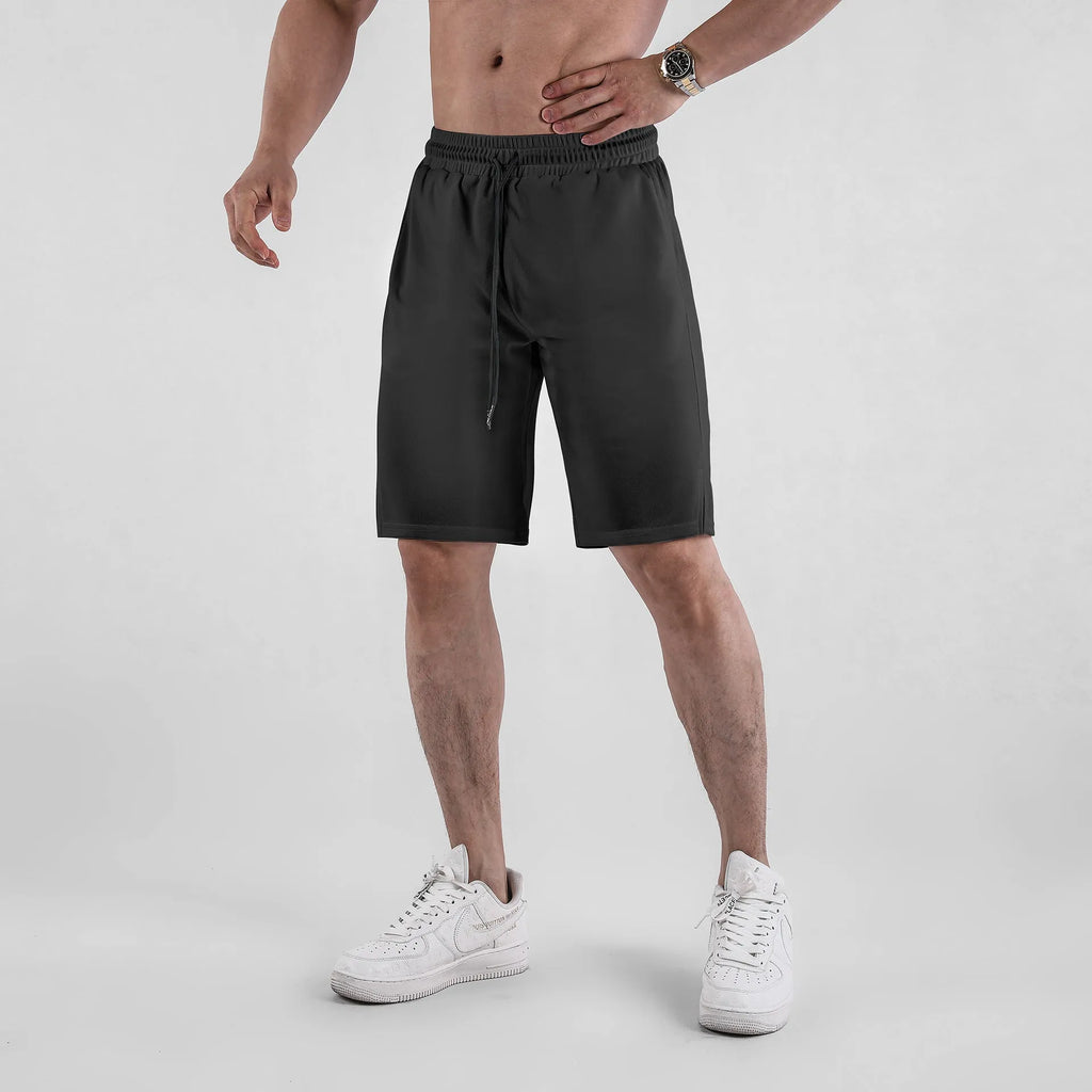 Man wearing black loose-fit quick-dry mesh shorts for summer sports.