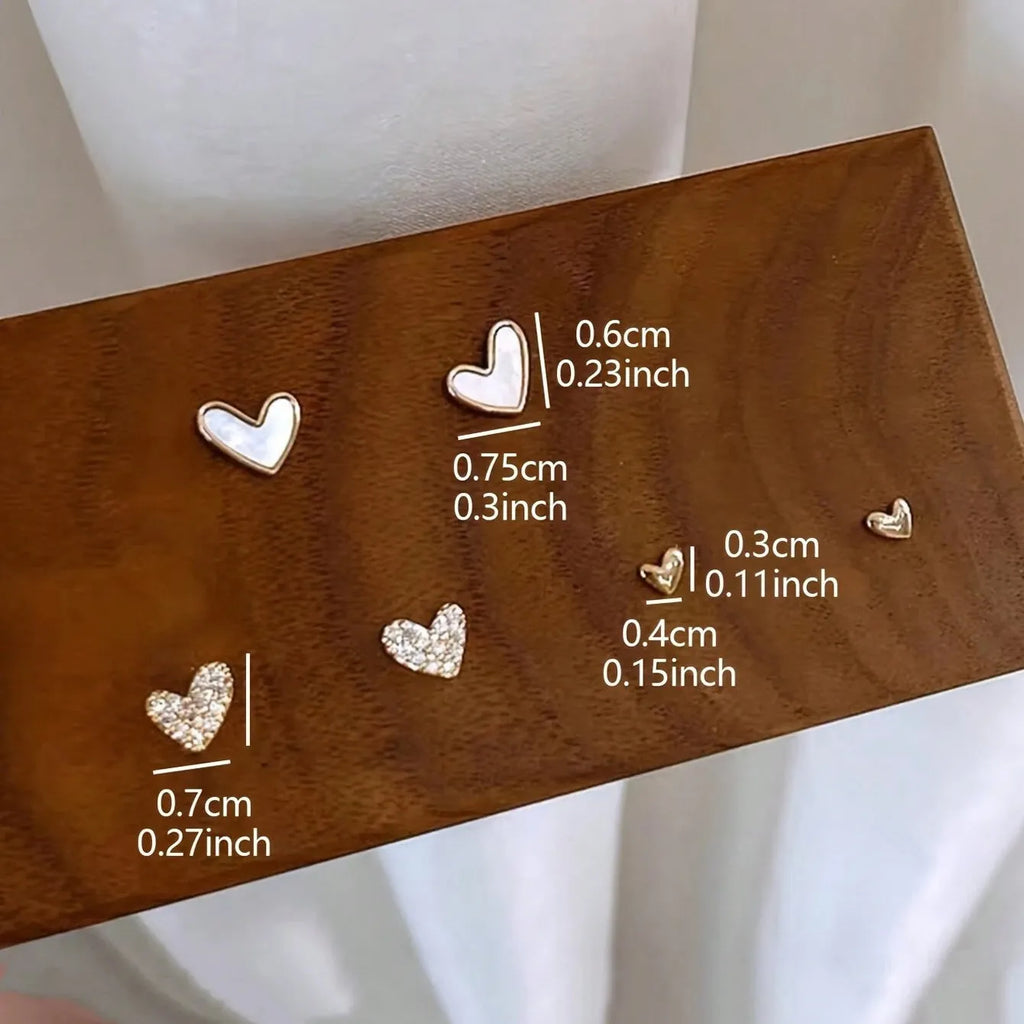 Three pairs of heart-shaped earrings with electroplated alloy construction in gold, black, pink and black-white colours