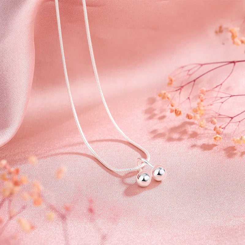 Silver necklace with cherry pendant on an adjustable snake bone chain.