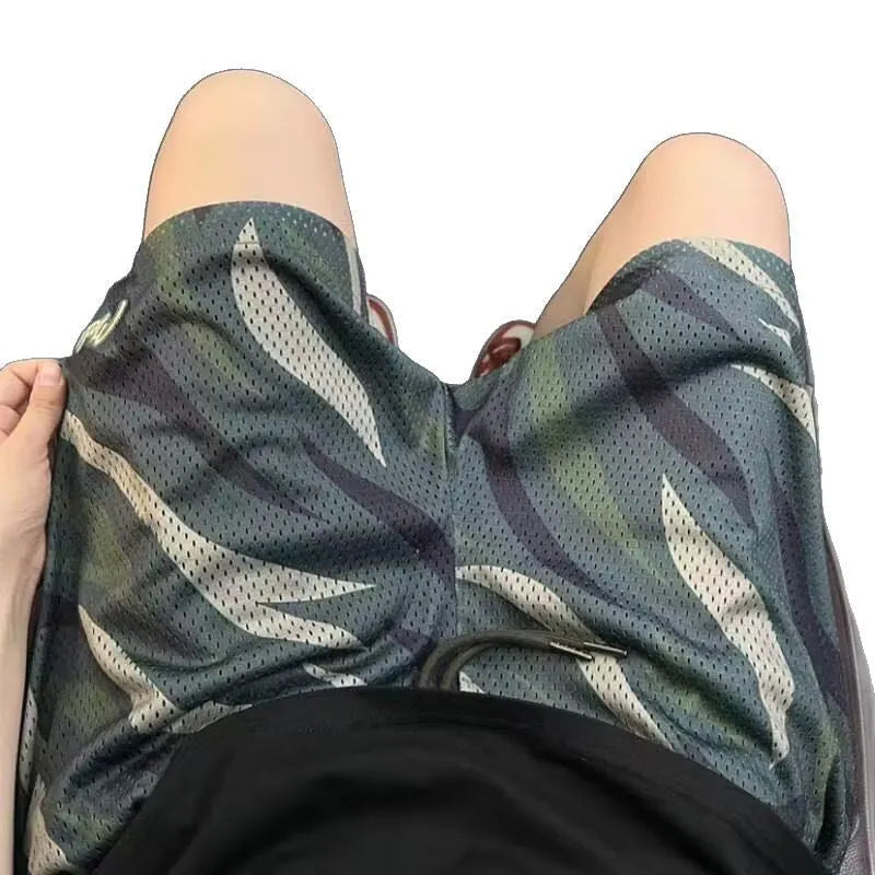 Men's straight cut camouflage mesh shorts in multi-tone green on a hanger.