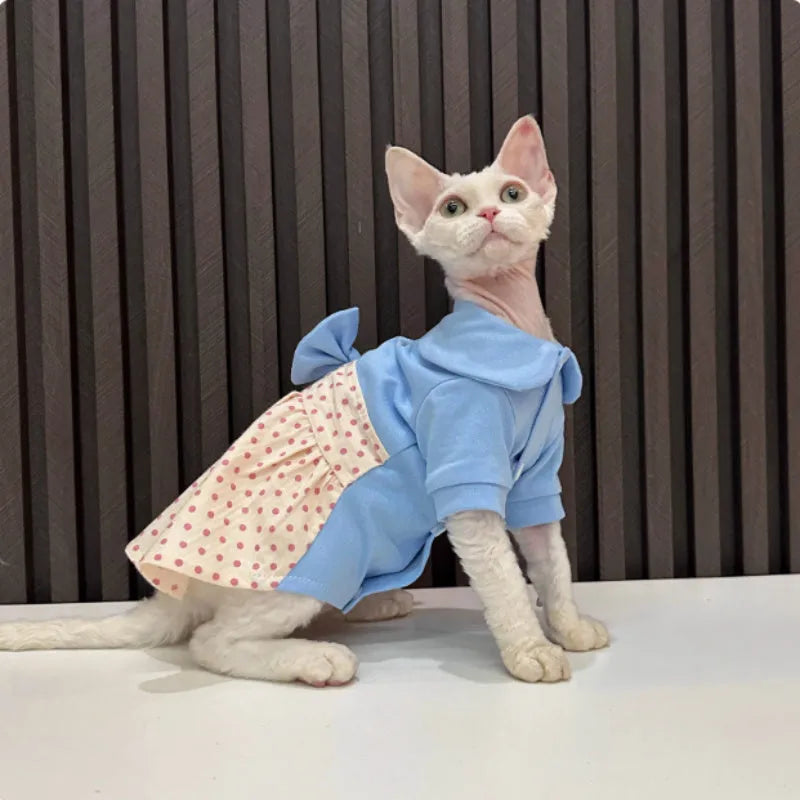 Hairless cat wearing a polka dot skirt with a detachable bow, lying down